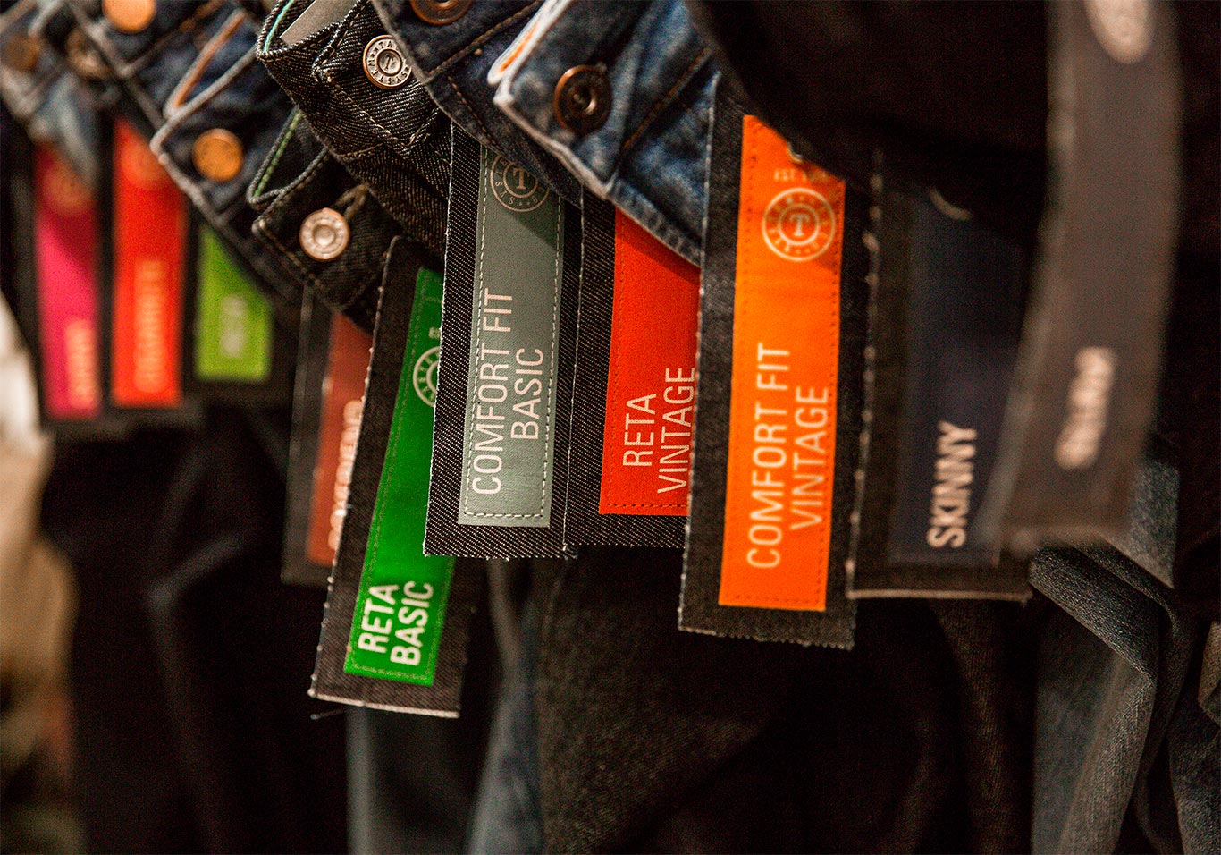 Diversas calças jeans penduradas com etiqueta a mostra
