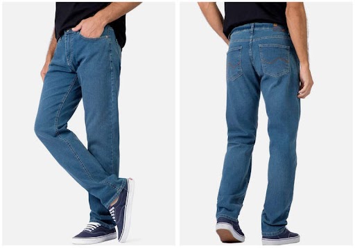 Homem usando calça jeans azul claro com mão no bolso e perna cruzada