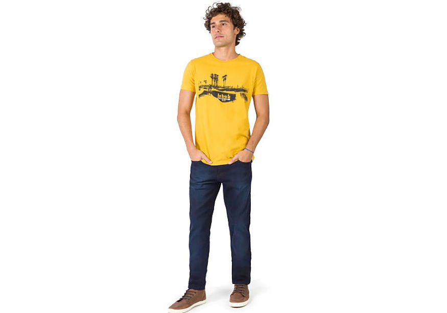 modelo veste t-shirt estampada amarela calça jeans lavagem escura com tênis 