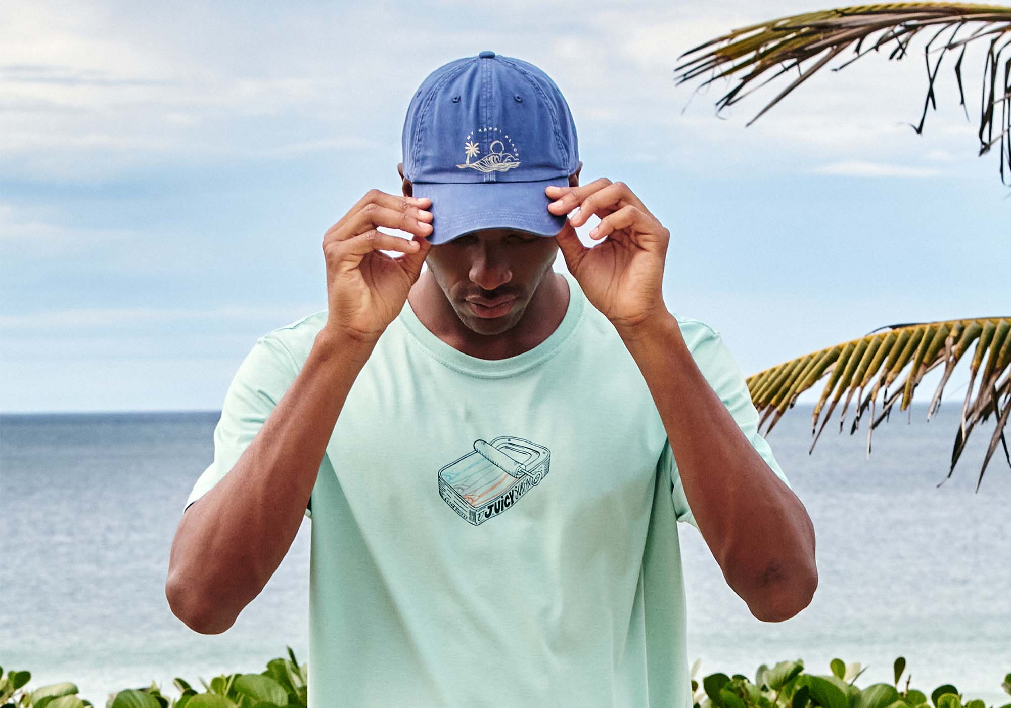 Jovem usando camiseta e boné azul na praia