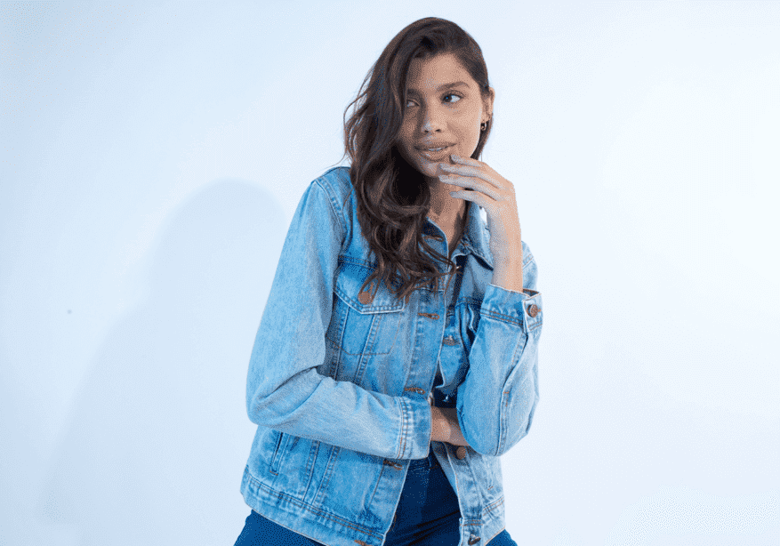 modelo com jaqueta jeans com a mão no rosto