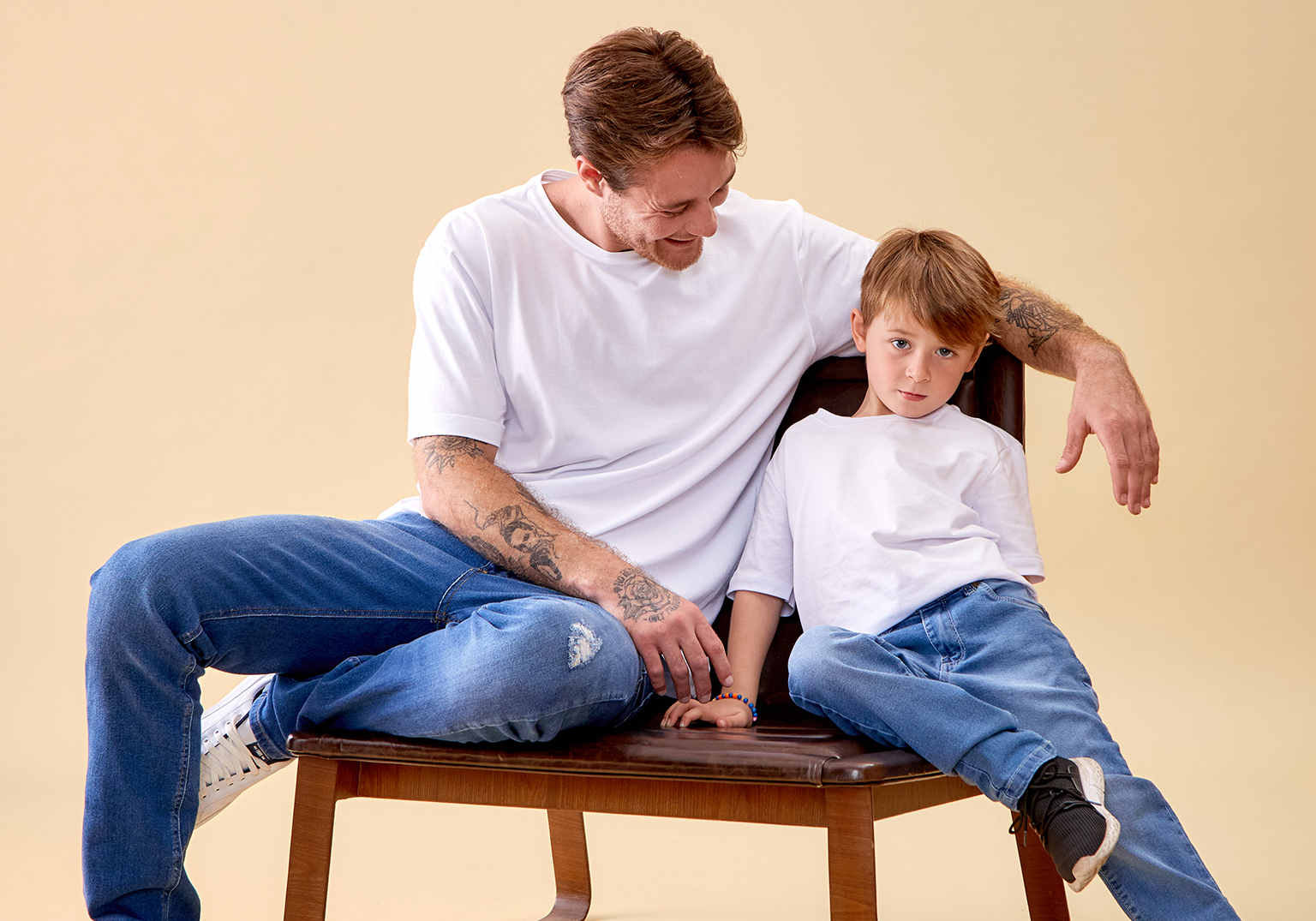 Pai e filho sentados em uma cadeira sorrindo juntos