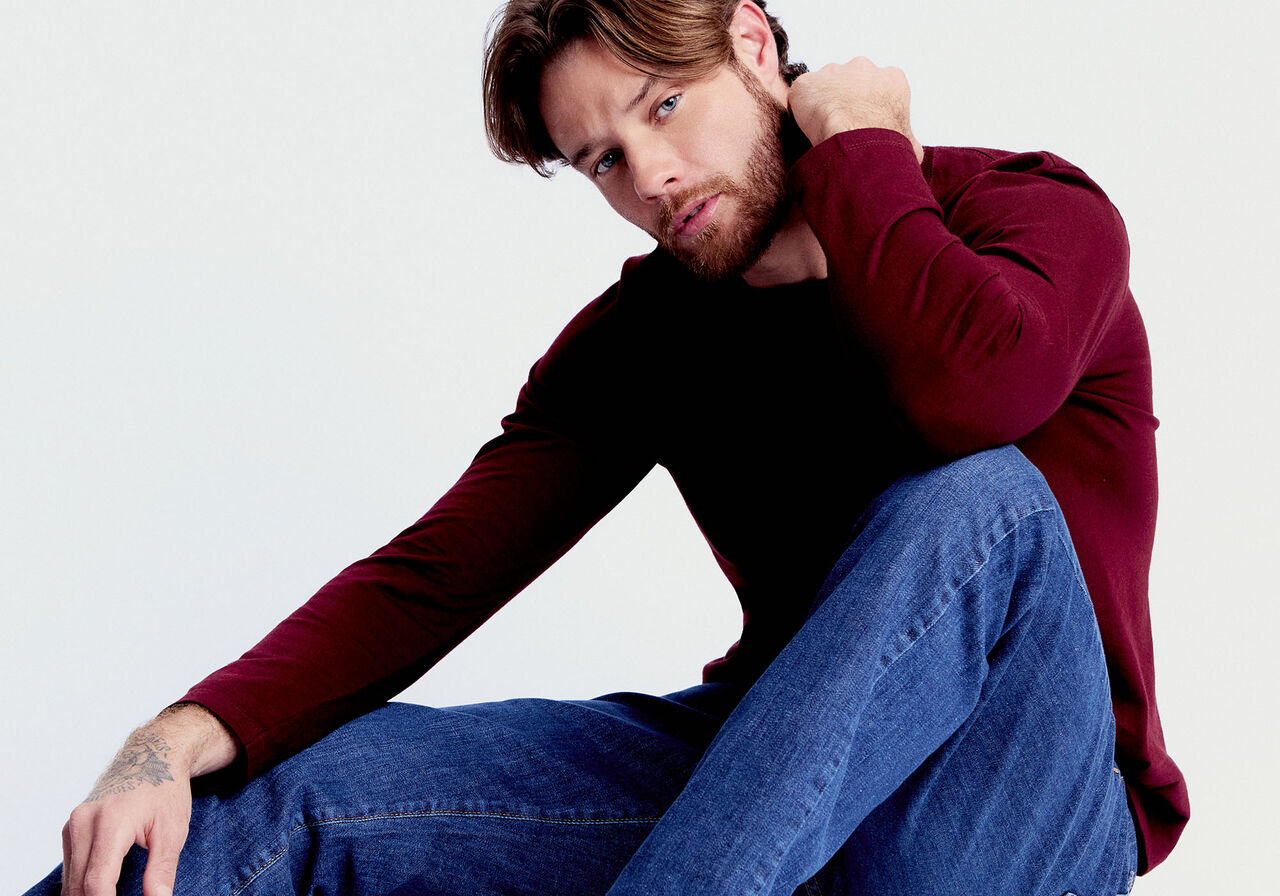 Homem com barba usando camisa marrom e jeans